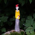 Ceramiczna stojąca figurka uśmiechniętego skrzata w żółtej bluzie i czerwonej czapce trzymającego muchomora w ręku.jpg